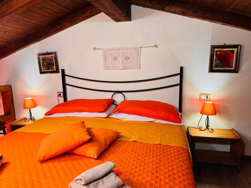 a bedroom with a bed with orange pillows and two lamps at Lilly's House in Monteponi