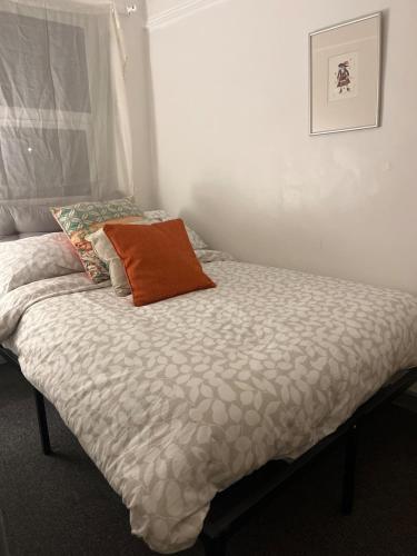 a bed with an orange pillow on top of it at Mansfield House in Norwich