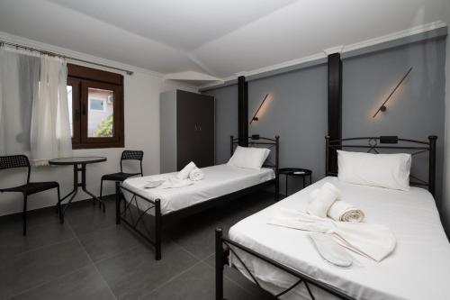 zwei Betten in einem Zimmer mit Tisch und Stühlen in der Unterkunft Marlen Luxury Studios & Apartments in Platamonas