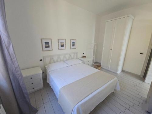 a white bedroom with a white bed and a door at camera vicino a mare e pineta in Follonica