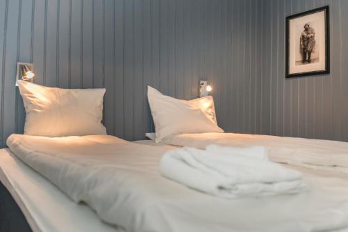 a bedroom with two beds with white sheets and pillows at Rorbuene Svolvær Havn in Svolvær