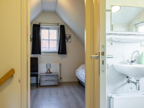 a bathroom with a sink and a bed in a room at Limosa in Hippolytushoef