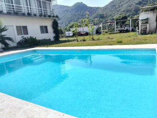 a large blue swimming pool next to a house at Mi casa de campo Tlayacapan in Tlayacapan