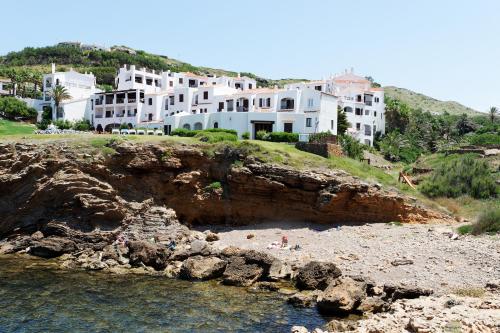 a group of white houses on a hill next to the water at Comitas Tramontana Park in Fornells