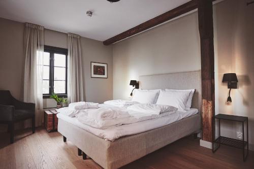 a bedroom with a large bed with white sheets at Havn Hotell og Restaurant in Skudeneshavn