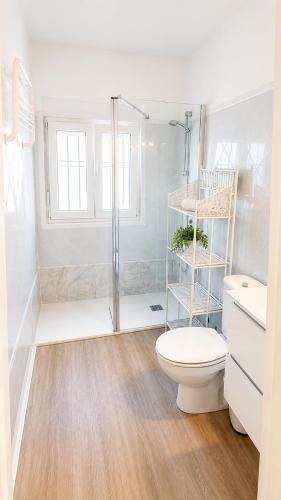 a white bathroom with a toilet and a shower at Apartamentos Larga 70 in El Puerto de Santa María
