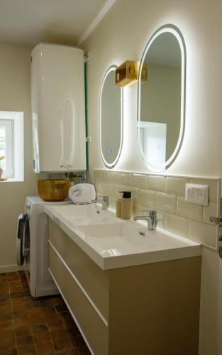 a bathroom with a sink and two mirrors at Gites Lisael et le 1808 proches Puy DuFou in Mauléon