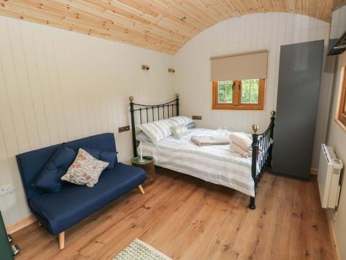 ein Schlafzimmer mit einem Bett und einem blauen Sofa in der Unterkunft Cwtch Y Bugail 1 in Llandeilo