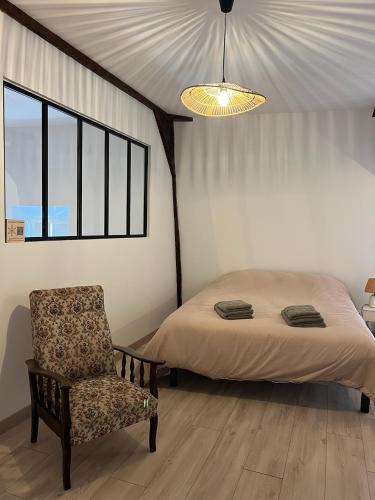 a bedroom with a bed and a chair and a lamp at Chez Simone et Marguerite in Luzy