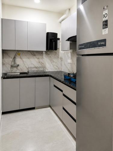 a kitchen with white cabinets and a refrigerator at The Elite Luxury Suite in Dehradun