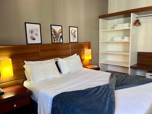 a bedroom with a bed with white sheets and pillows at Studio apartment in downtown Joinville, SC in Joinville