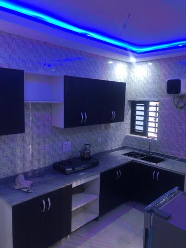 a kitchen with black cabinets and a blue light at House 22 Apartments in Kubwa