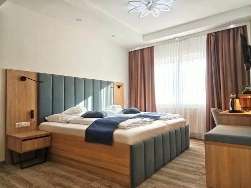a bedroom with a large bed with a blue headboard at Wellness Hotel Garni Krone in Baiersbronn