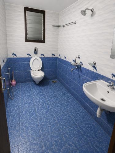 a blue tiled bathroom with a toilet and a sink at Selfia apartments 2BHK in Majorda