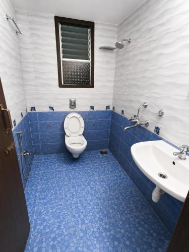 a blue and white bathroom with a toilet and a sink at Selfia apartments 2BHK in Majorda