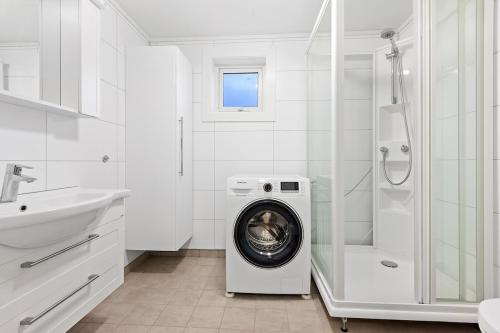 a white bathroom with a washing machine in a washer at Roksoy for rent in Sortland