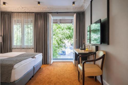 a bedroom with a bed and a desk and a window at Hotel Villa Nord Hamburg-Airport in Hamburg