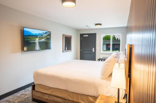 a bedroom with a white bed and a desk at Alpine Inn Abbotsford in Abbotsford
