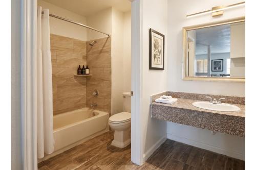a bathroom with a sink and a tub and a toilet at Garland Inn & Suites near Dallas TX in Garland