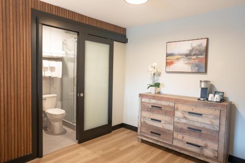 a bathroom with a toilet and a wooden dresser at Alpine Inn Abbotsford in Abbotsford