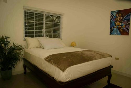 a large bed in a bedroom with a window at Caymanas Estate House in Portmore