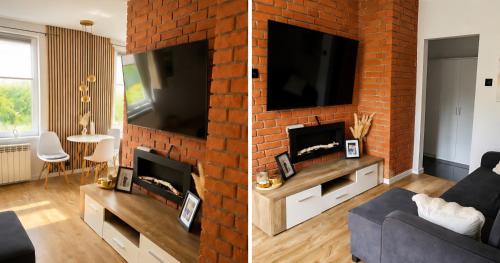 a living room with a brick wall with a tv at Kamienica Centrum in Pisz