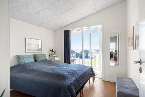 a bedroom with a blue bed and a balcony at 1166-Ringkobing-Havstien-388 in Søndervig