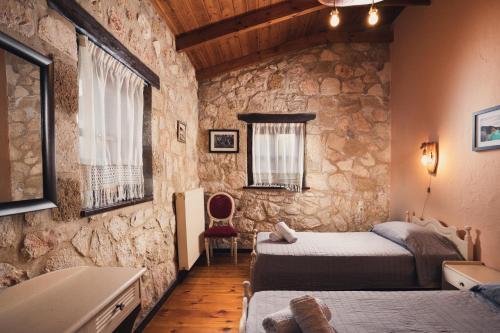 a bedroom with two beds and a stone wall at Kidóni Villas in Gaïtánion