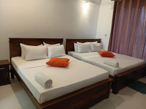 two beds with orange and white pillows in a room at Silina Airport Residence & Transit Hotel in Katunayaka