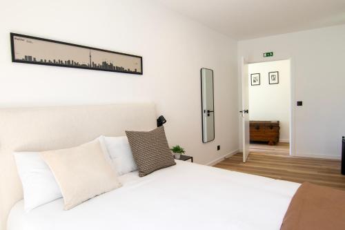a white bedroom with a large bed with white pillows at Latitude Guest House in Cantanhede