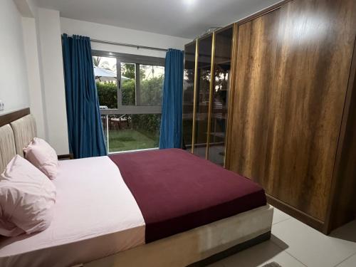 a bedroom with a bed with blue curtains and a window at Condo in Marassi Marina in El Alamein