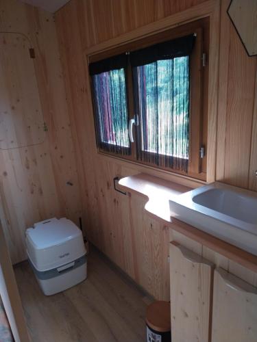 a bathroom with a toilet and a sink and a window at La Roulotte de piégut in Piégut-Pluviers