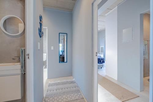 a hallway with white walls and a door with a rug at Meraki Sands in Hermanus