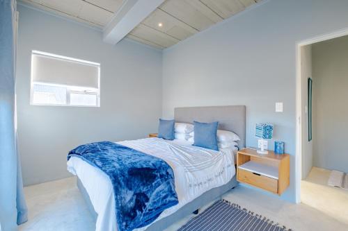 a white bedroom with a bed with blue pillows at Meraki Sands in Hermanus