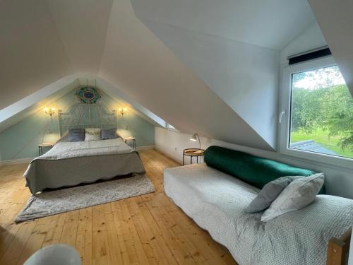 a attic bedroom with two beds and a window at Dove Cottage Chatka 35 Chalmová in Bystričany
