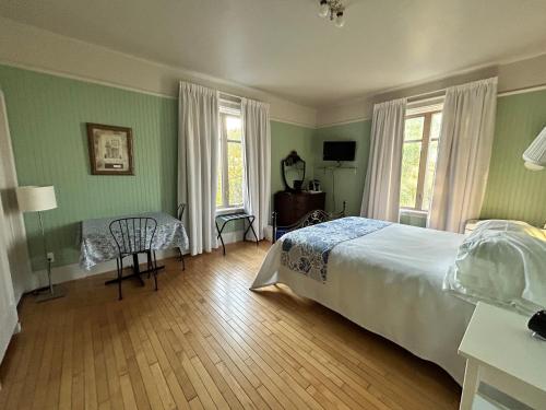 a bedroom with green walls and a bed and a table at Auberge La Seigneurie in Matane