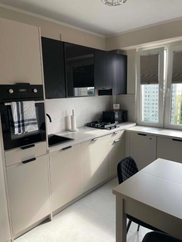 a kitchen with white cabinets and a table in it at Apartament Rubinkowo in Toruń