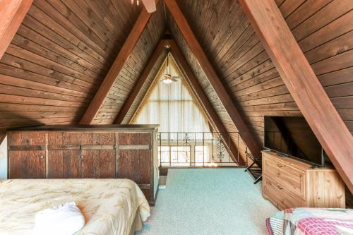 a attic bedroom with a bed and a tv at Charming, lakefront A-frame with private dock, lakeside gazebo, spacious deck in Bumpass