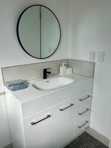 a bathroom with a white sink and a mirror at Hildas Villa in Arorangi