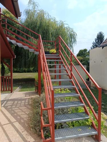 a staircase with a red railing with flowers on it at Fűzfa Apartmanház in Tamási