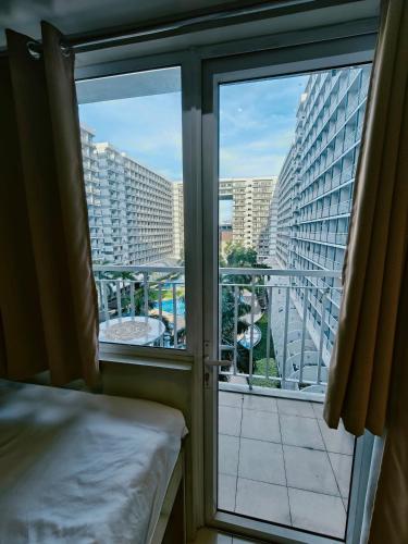 a room with a bed and a view of a balcony at MOA shell residences - JOSH in Manila