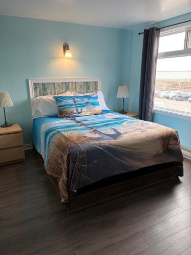 a bedroom with a bed with blue walls and a window at Shoreline Suites in Digby