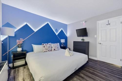 a bedroom with a white bed and a blue wall at Blue Cave Escape - Pool Hot Tub & Shuttle in Blue Mountains