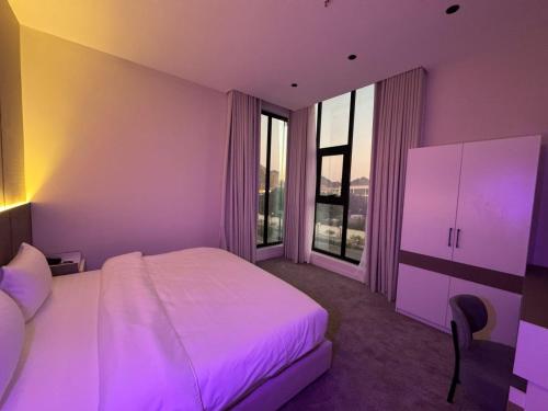 a bedroom with a white bed and purple lighting at رست للشقق المخدومة in Medina