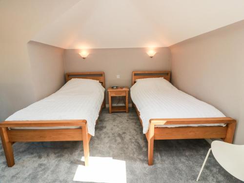 two beds in a small room with two tables at Sundale in Strathaven