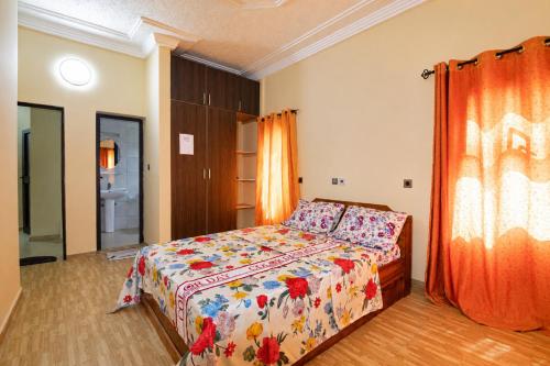 a bedroom with a bed with a floral bedspread at Résidence APOW in Agogoudjou