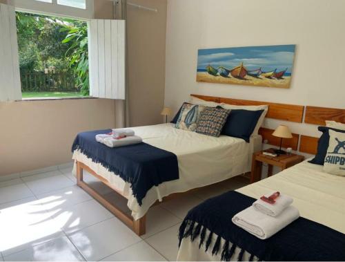 a bedroom with two beds and a window at Pousada Cacau e Dendê in Barra Grande