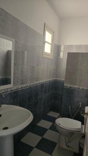 a bathroom with a white toilet and a sink at Appartement kantaoui in Sousse