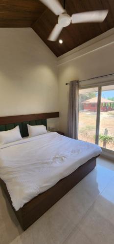 a bedroom with a large bed and a window at Saavi Resort Shrivardhan in Srīvardhan