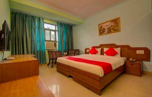a bedroom with a bed with red pillows and a desk at Hotel Shaan- M I Road City Centre in Jaipur